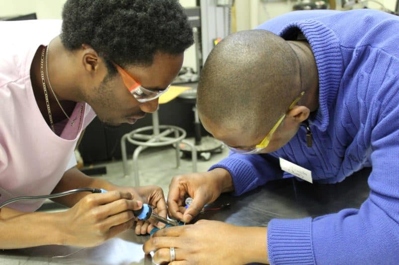 Two teachers solder a SeaPerch robot